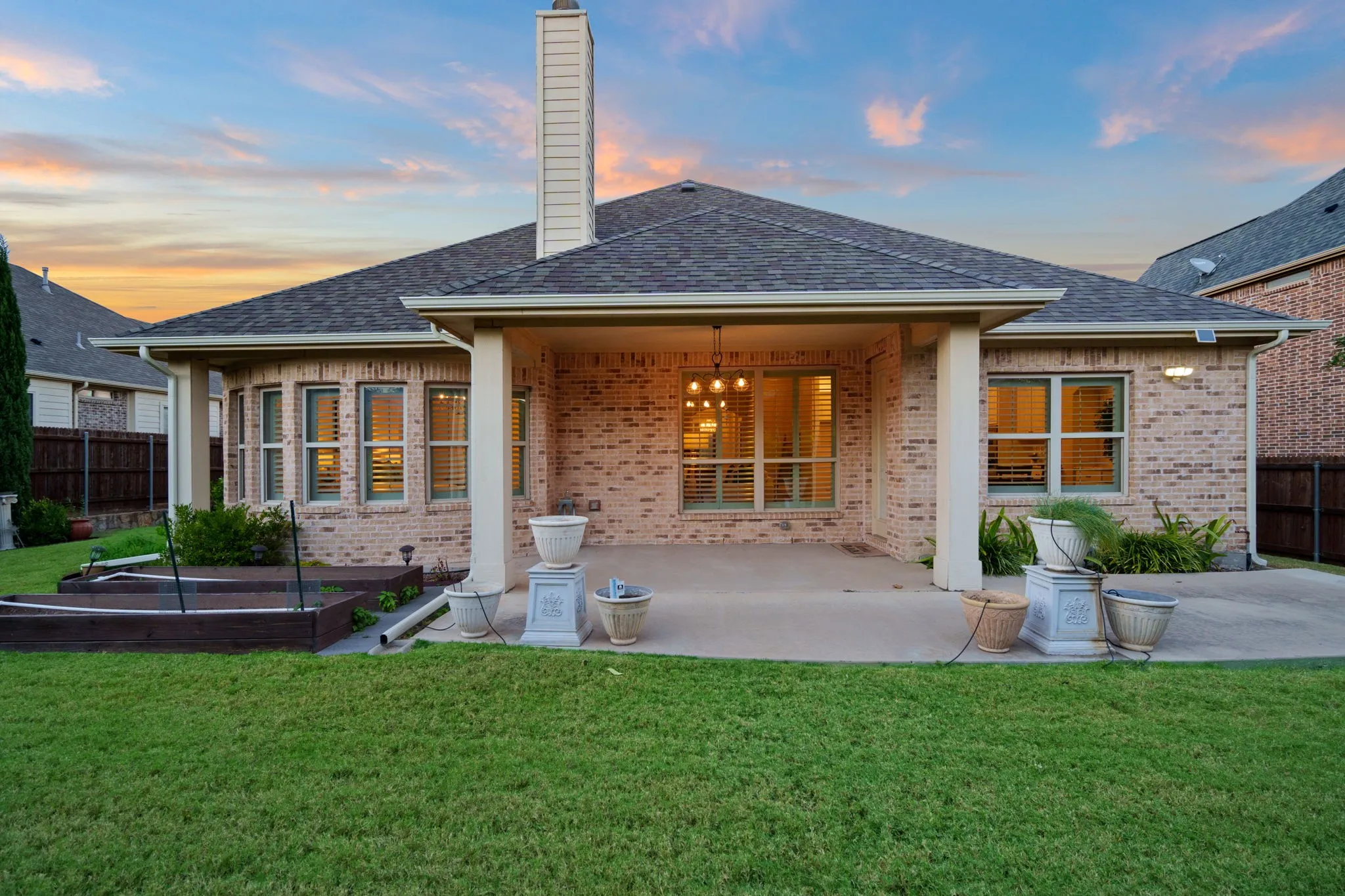 Back of house at dusk featuring a covered patio