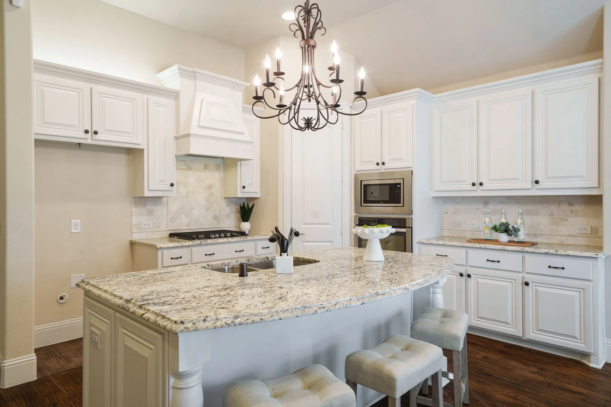Spacious kitchen with expansive granite counters, elegant lighting, and seating at the oversized island.