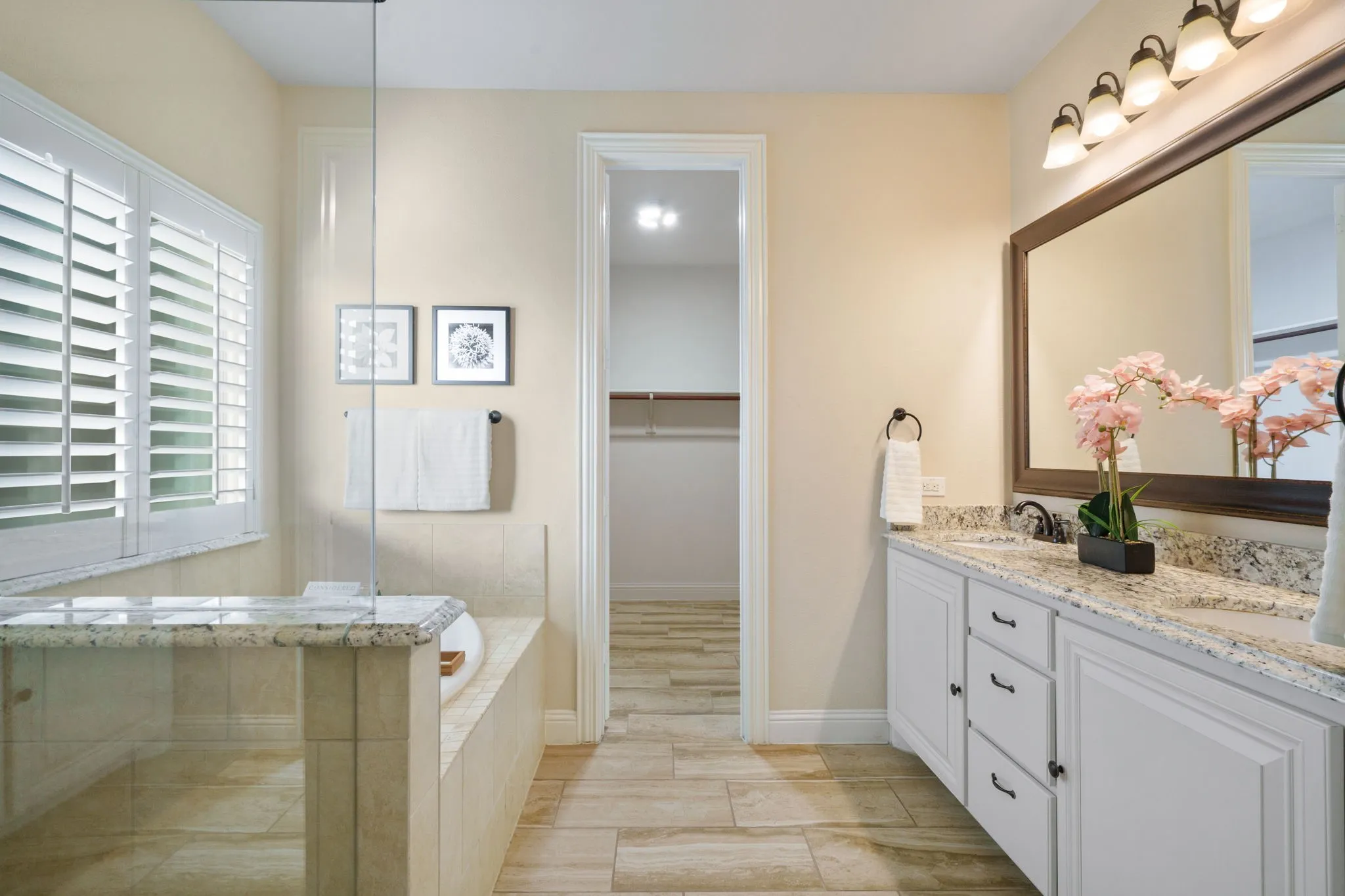 Primary bath featuring granite counters, dual vanities, and direct access to a large walk-in closet.