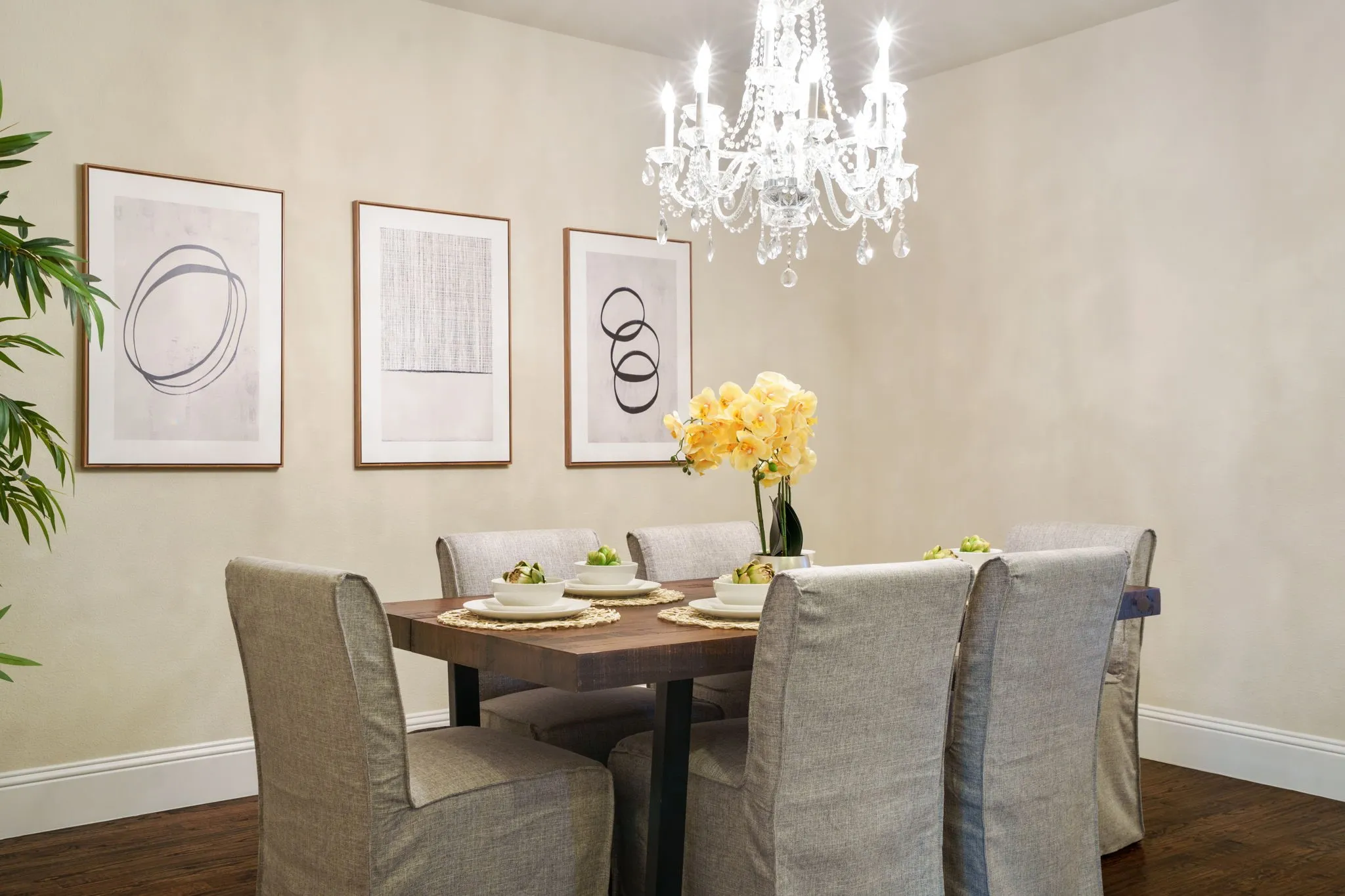 Elegant dining room with modern art, a crystal chandelier, and soft neutral tones — perfect for intimate gatherings.