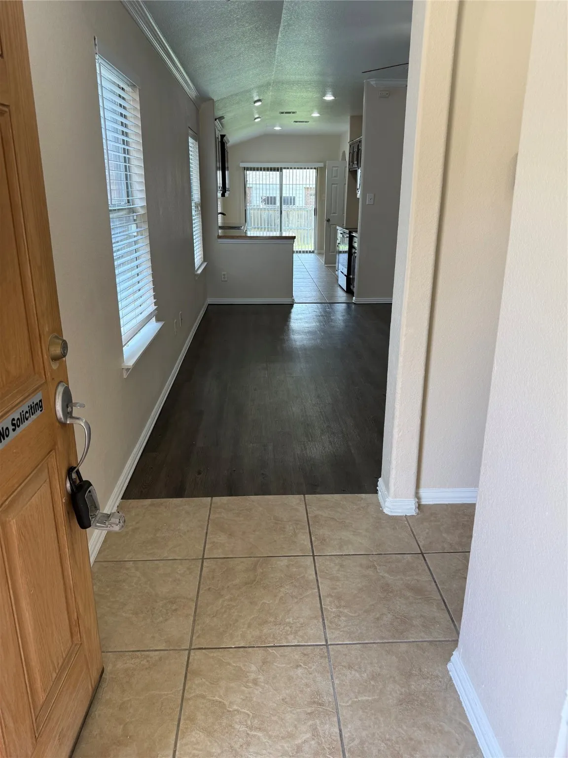 Corridor with lofted ceiling, light tile patterned floors, and a textured ceiling
