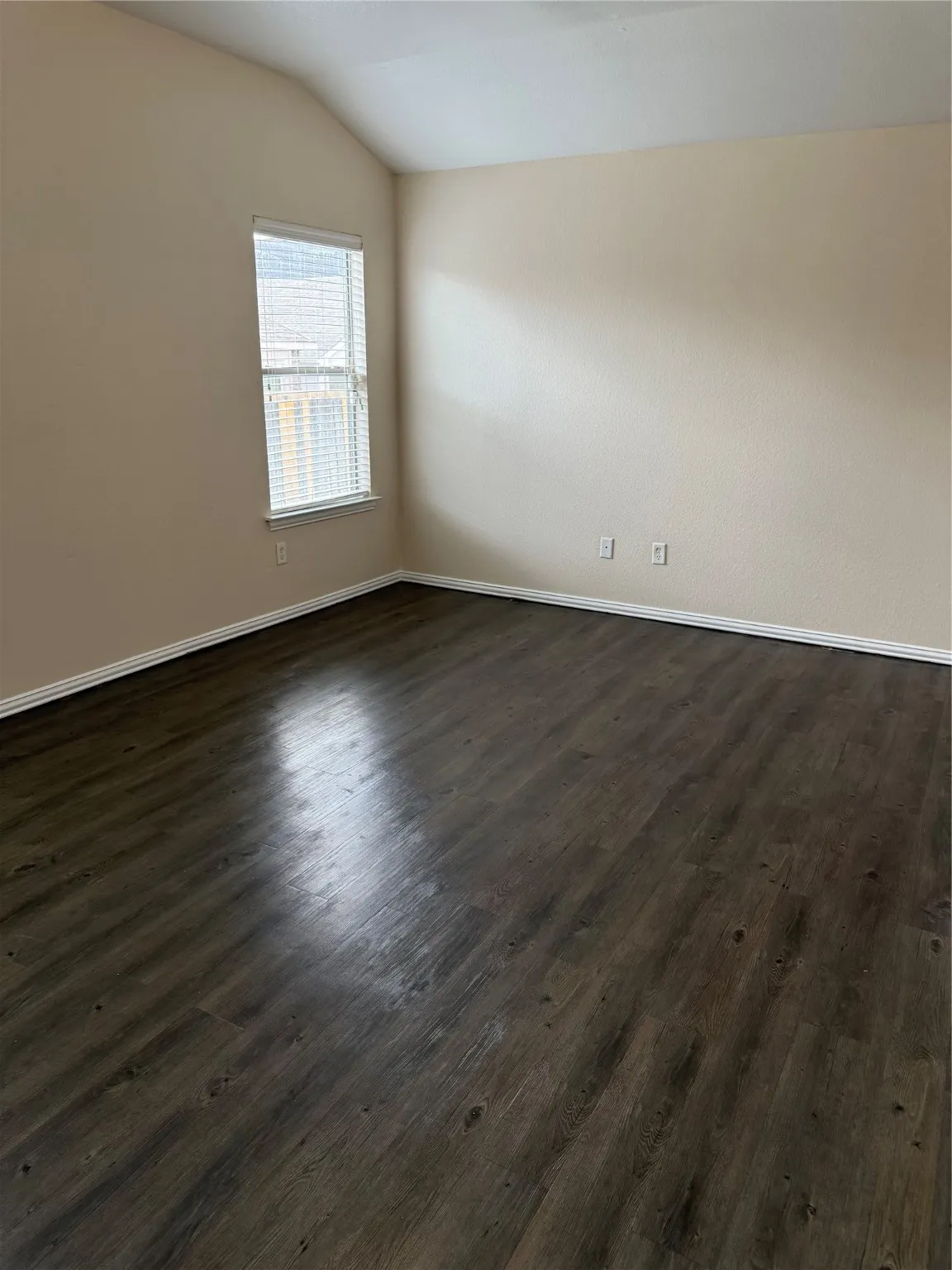 Unfurnished room with lofted ceiling and dark wood-type flooring