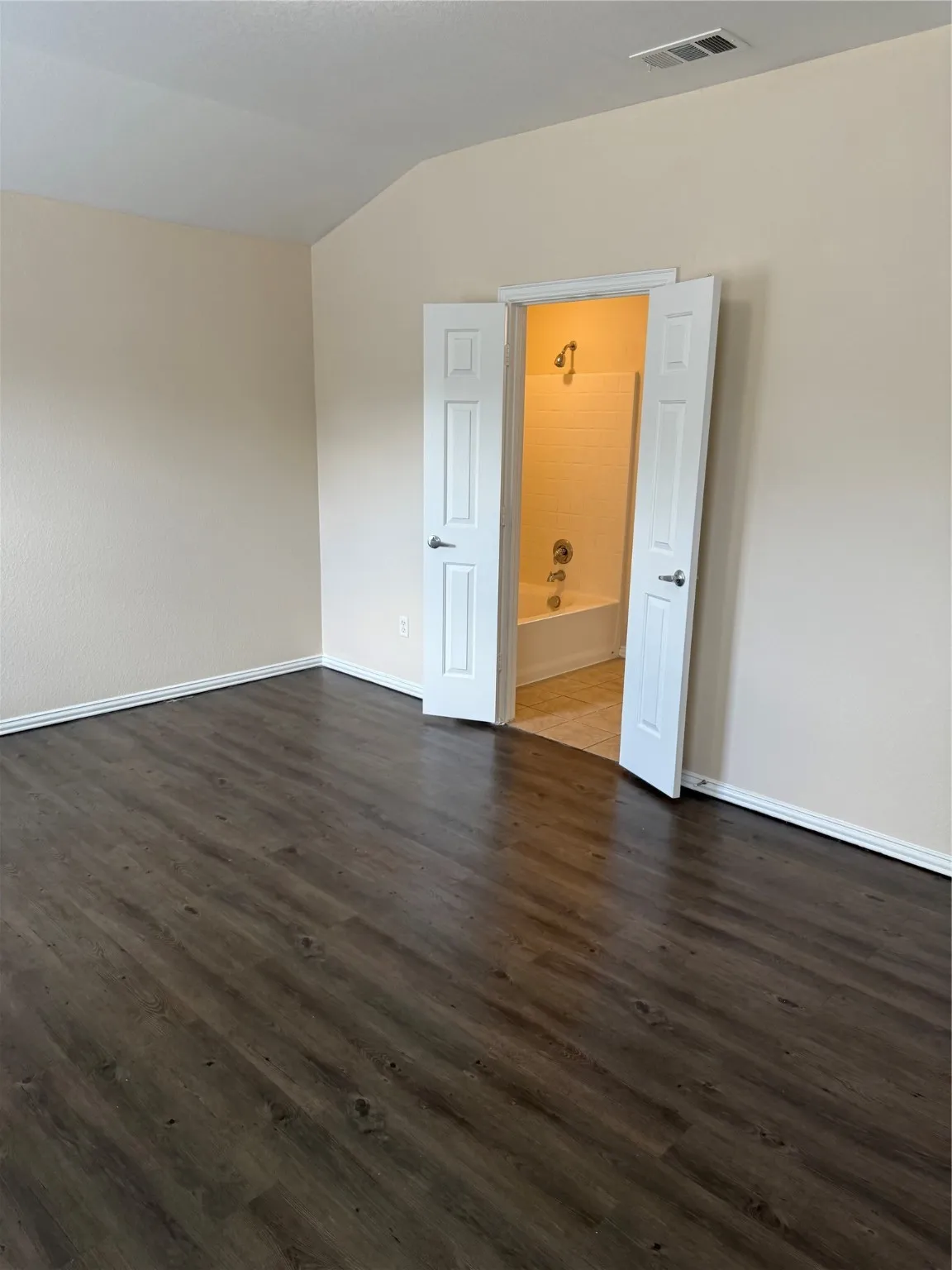 Unfurnished room featuring vaulted ceiling and dark wood-type flooring