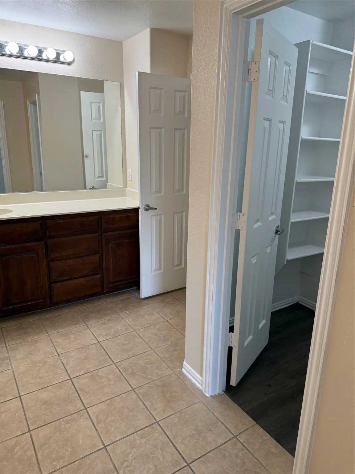 Full bath featuring vanity, light tile patterned flooring, and a spacious closet