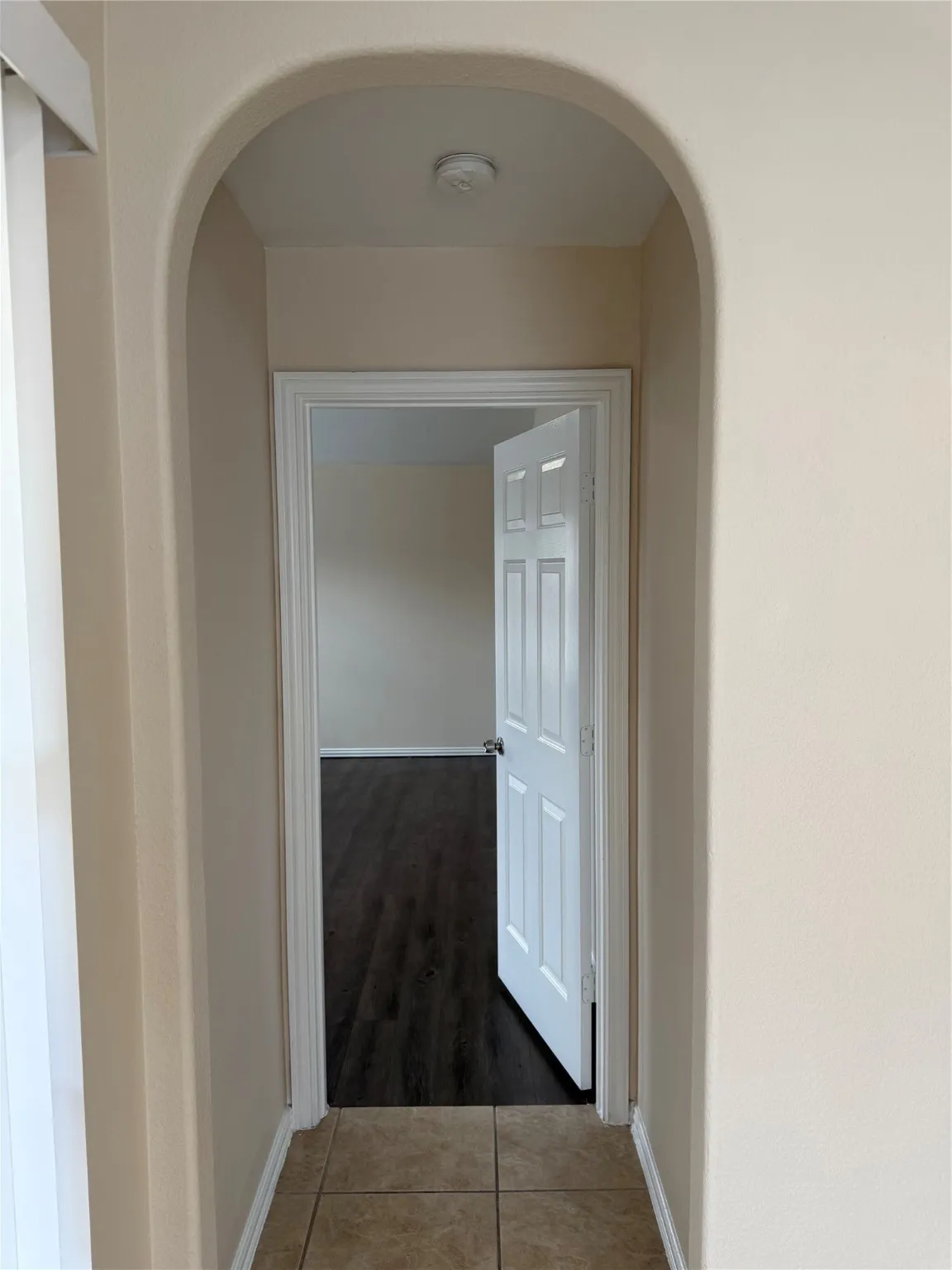 Corridor with arched walkways and tile patterned flooring