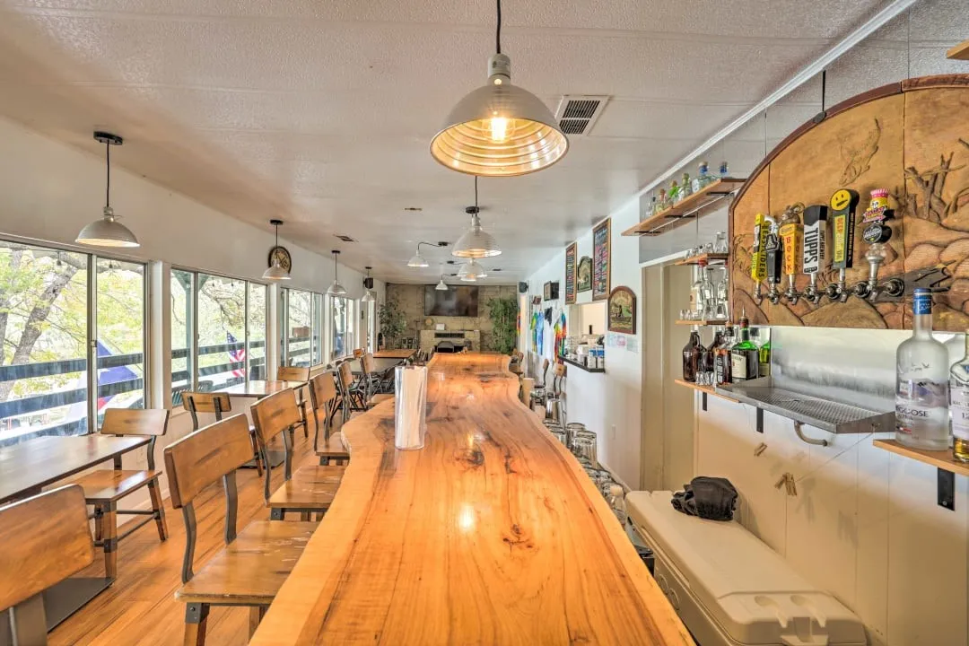 Dining area with a textured ceiling, a bar, and light wood finished floors