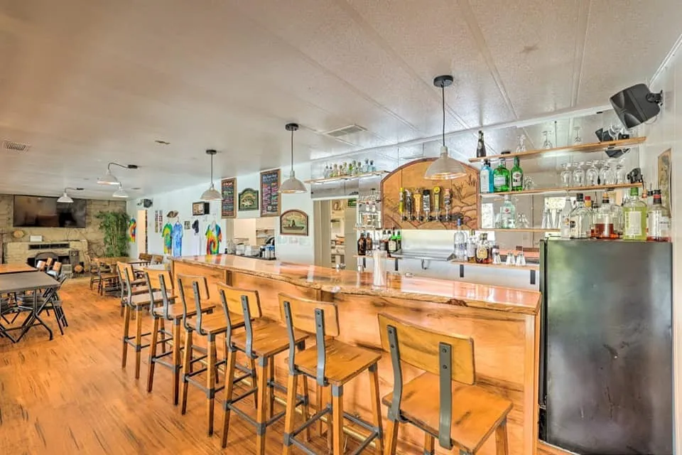 Community bar area featuring open shelves, decorative light fixtures, and a fireplace with raised hearth