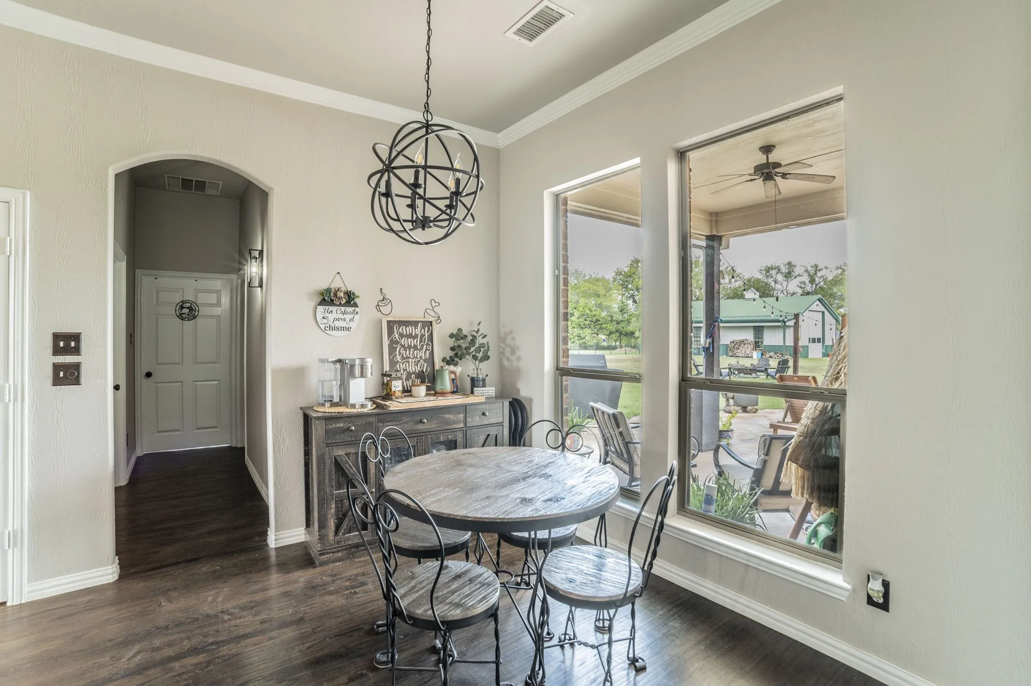 Dining area with ornamental molding, dark wood-style floors, arched walkways all overlooking the patio and back area of the property.
