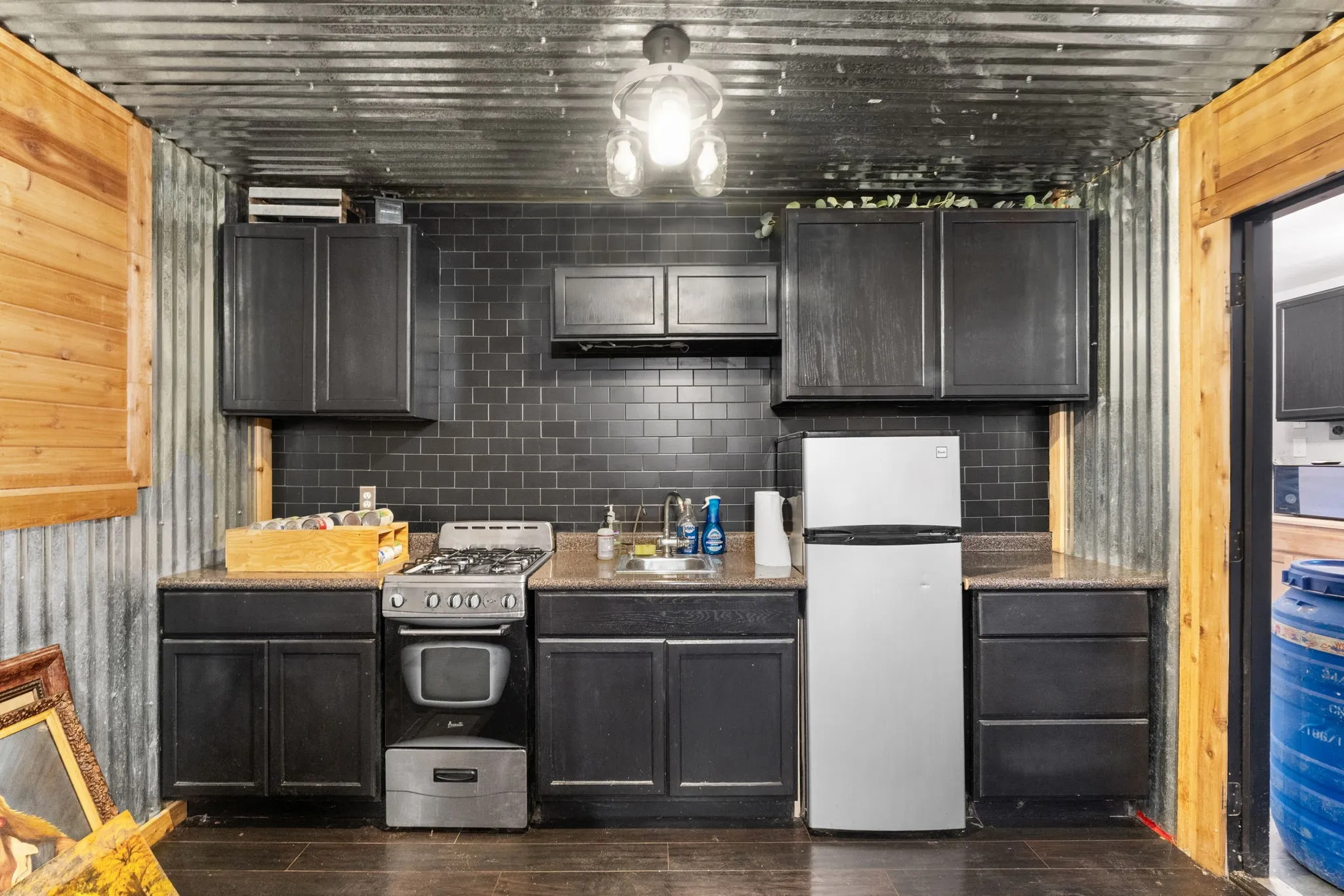 Kitchenette featuring dark cabinetry, a full-size range, a refrigerator, and a stainless steel sink