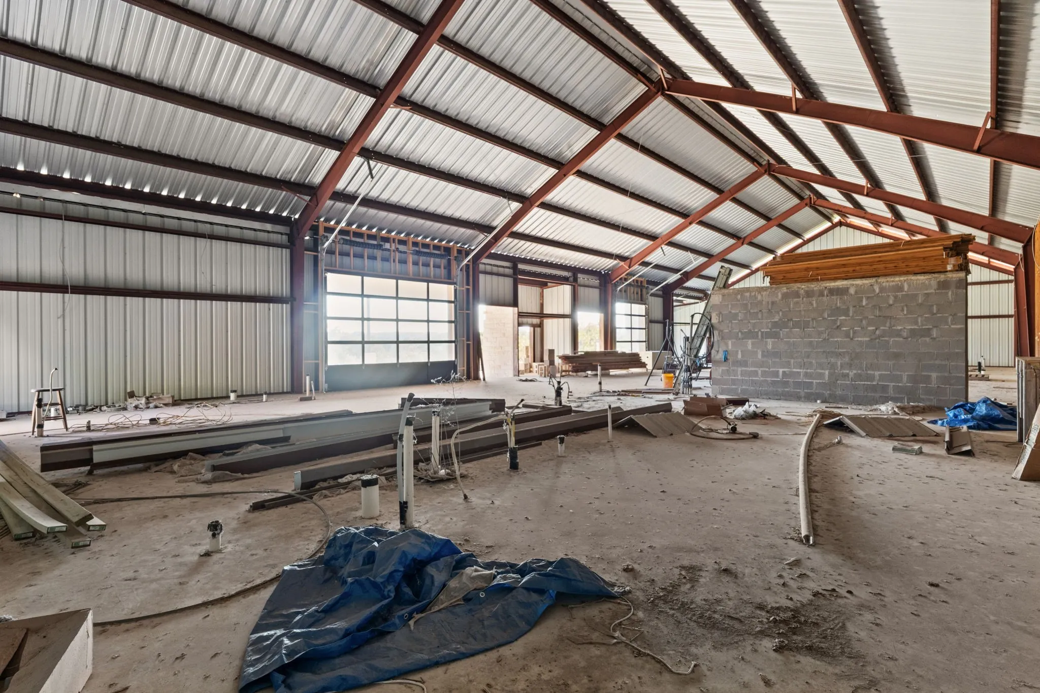 Spacious open-concept industrial interior featuring exposed steel truss framing and a corrugated metal roof