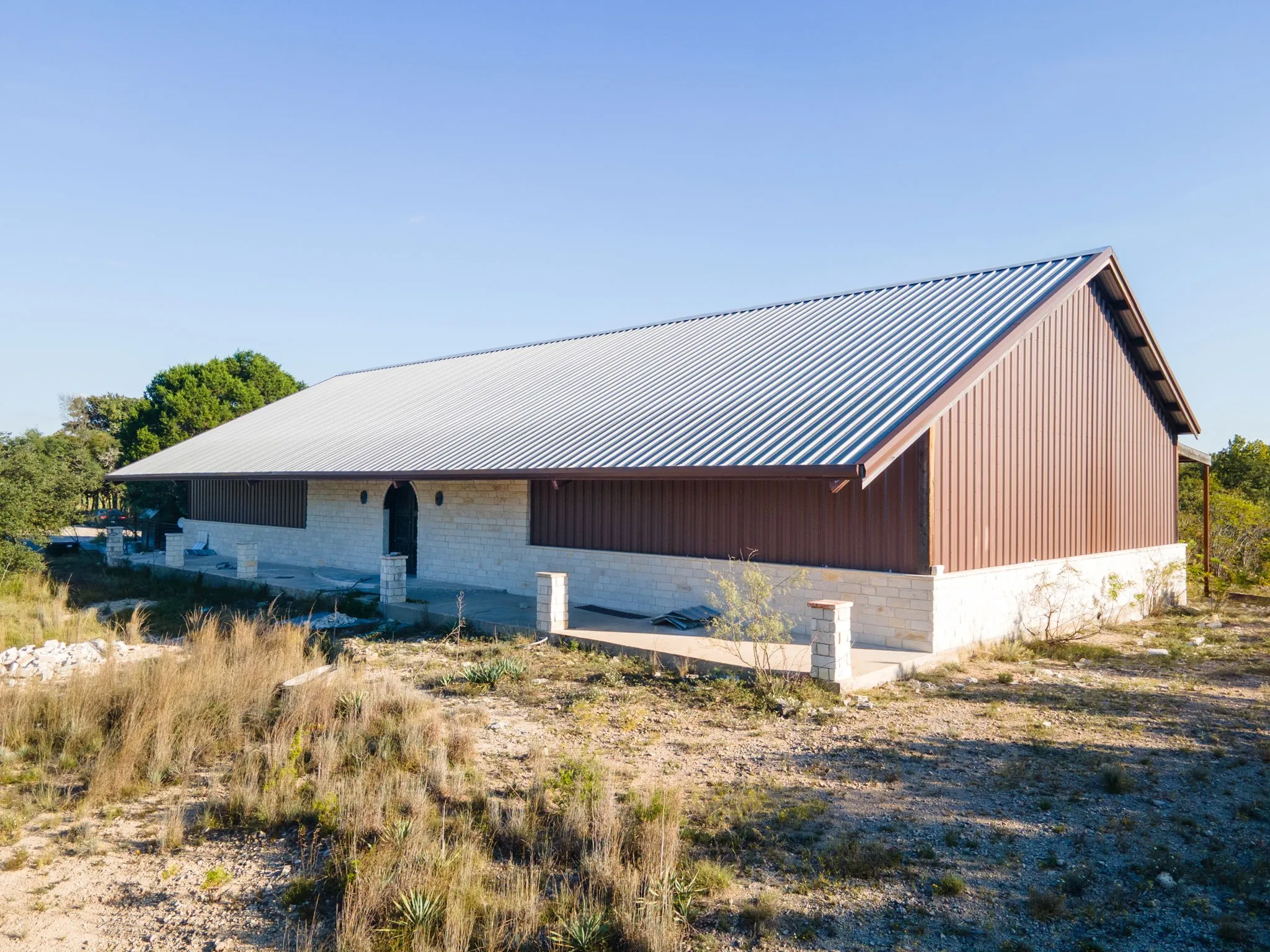 Expansive structure featuring a metal roof, brown siding, and a stone-clad base