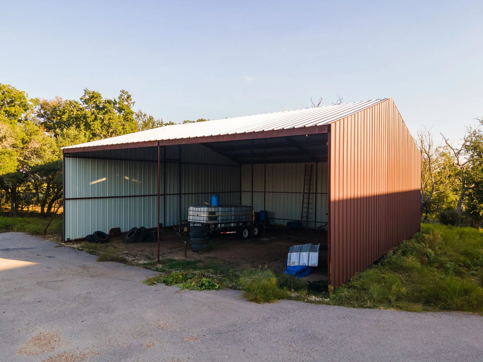 Spacious open-sided metal structure with a white corrugated roof, supported by dark metal beams