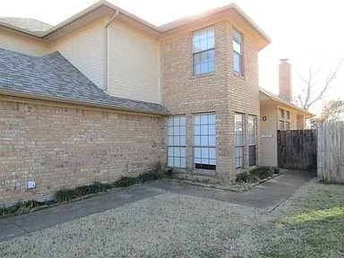 View of property exterior with brick siding and a chimney