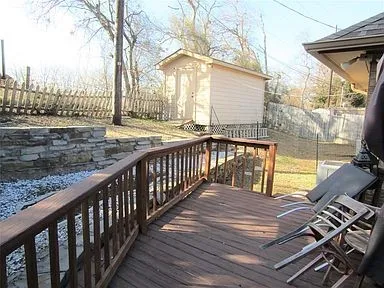 Wooden terrace featuring a fenced backyard and an outbuilding