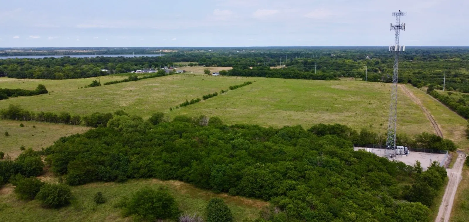 Aerial view of sparsely populated area featuring a large body of water and a tree filled landscape