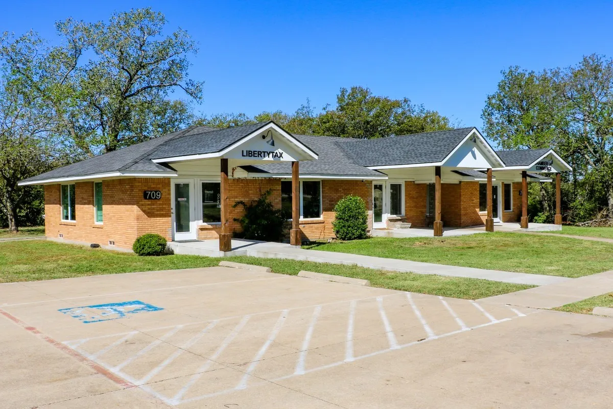 View of front facade featuring a front yard, brick siding, a porch, and roof with shingles