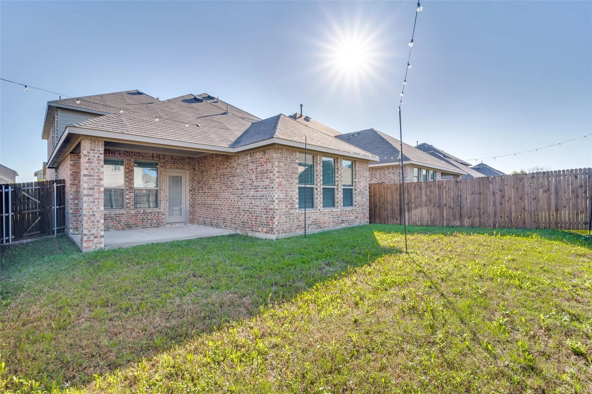 Rear view of house featuring a patio area, a fenced backyard, and brick siding