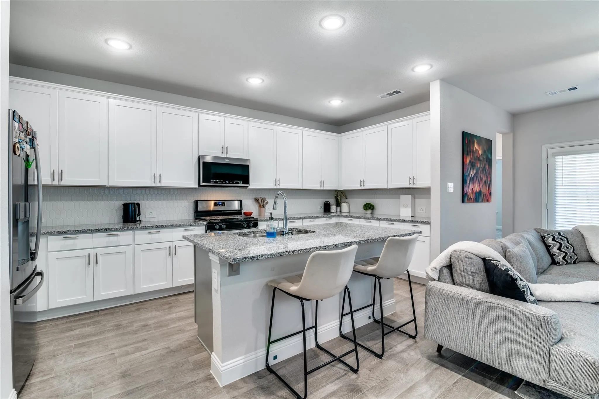 Kitchen with a kitchen breakfast bar, open floor plan, light stone countertops, stainless steel appliances, and a kitchen island with sink