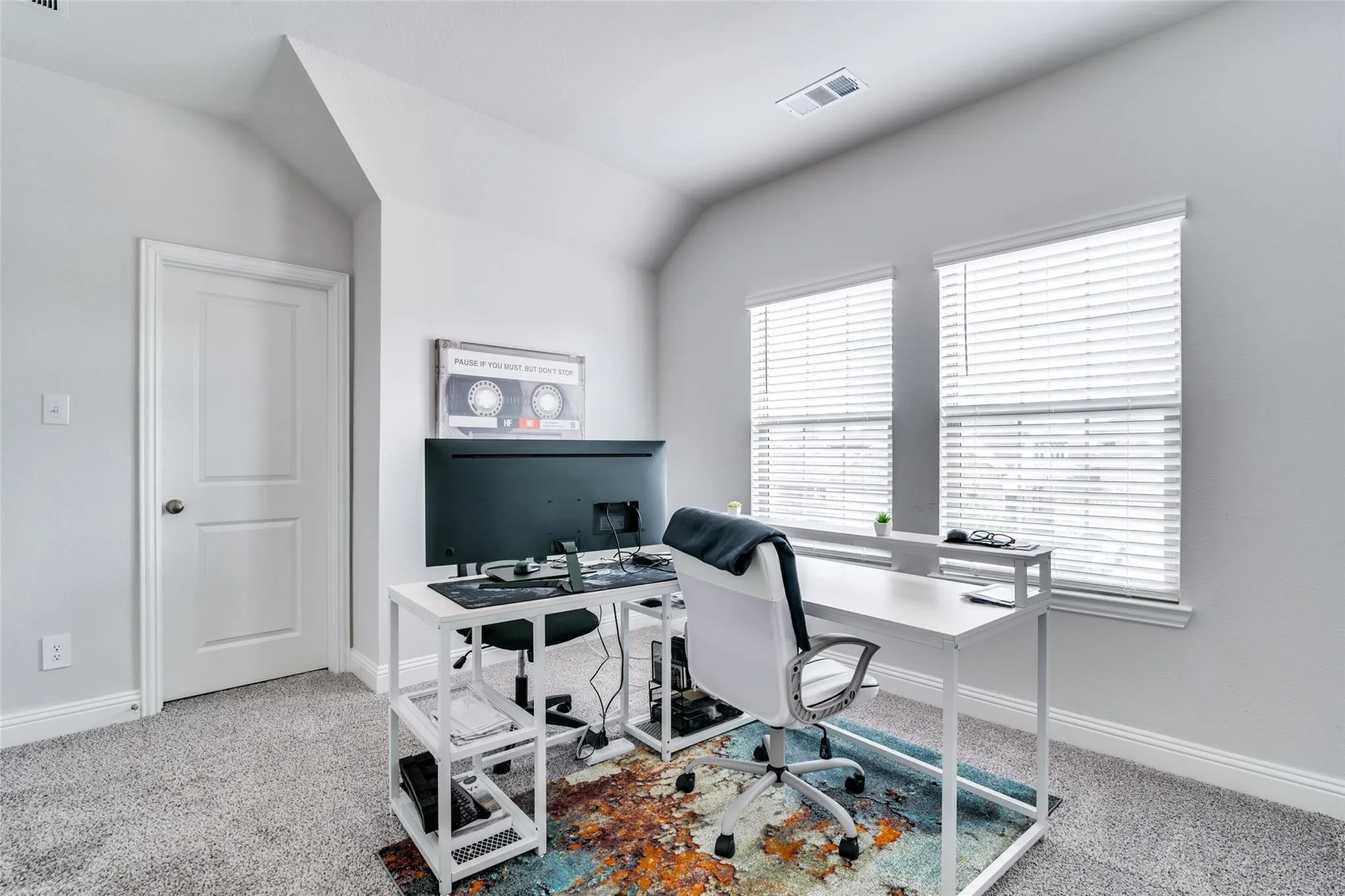 Home office with light carpet and lofted ceiling