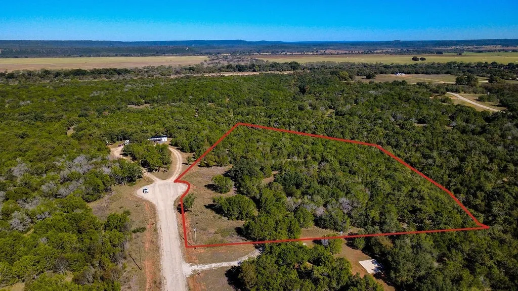 Aerial view of property's location featuring property parcel outlined and a heavily wooded area