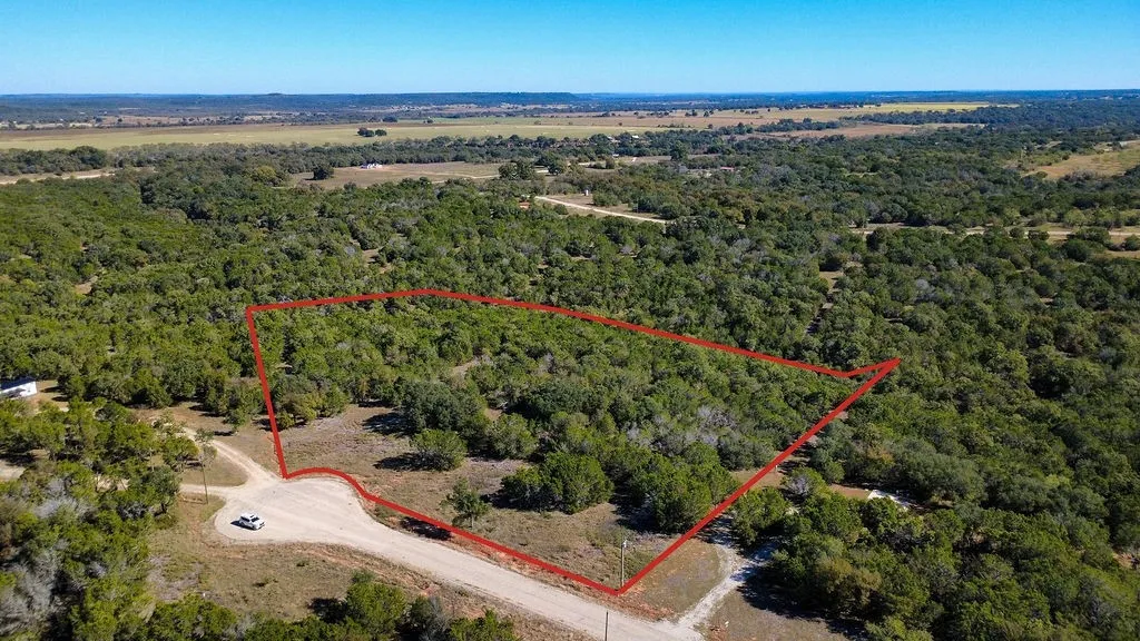 Aerial view of property and surrounding area with property boundaries highlighted and a forest