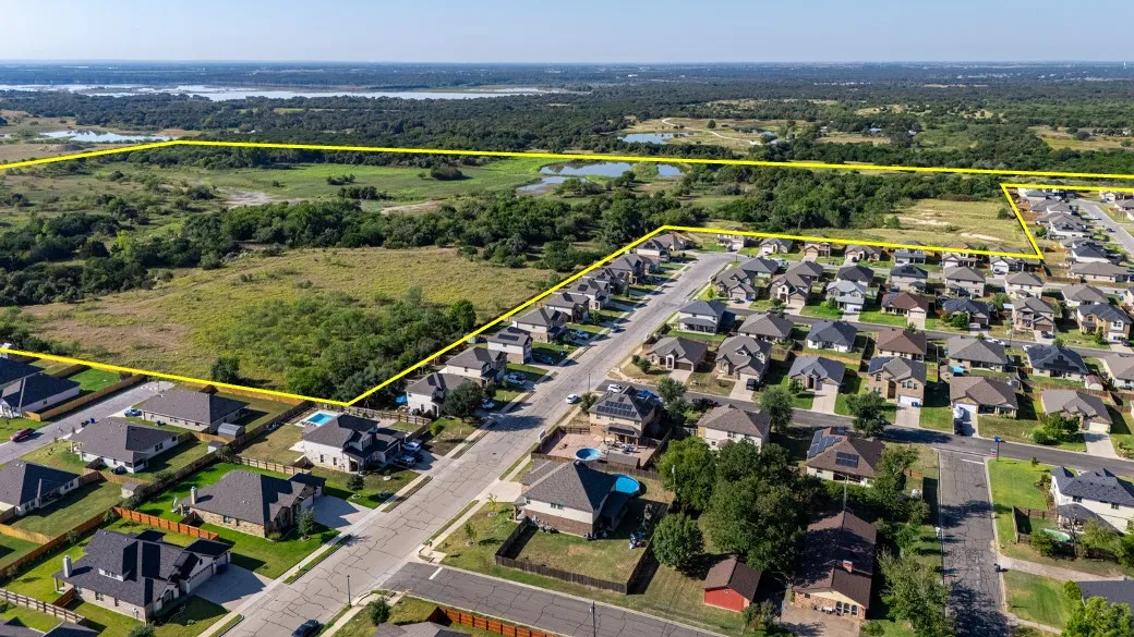 Aerial view of residential area featuring a large body of water and property parcel outlined