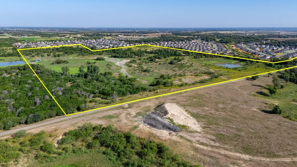 Aerial view of residential area with a nearby body of water and property boundaries highlighted