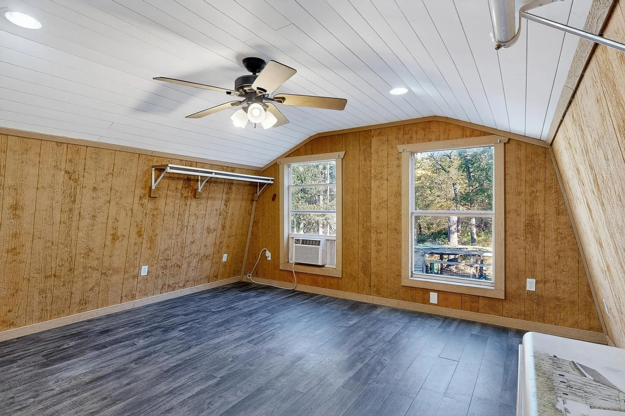 Bedroom featuring dark wood-style floors, wooden walls, vaulted ceiling, wooden ceiling, and ceiling fan