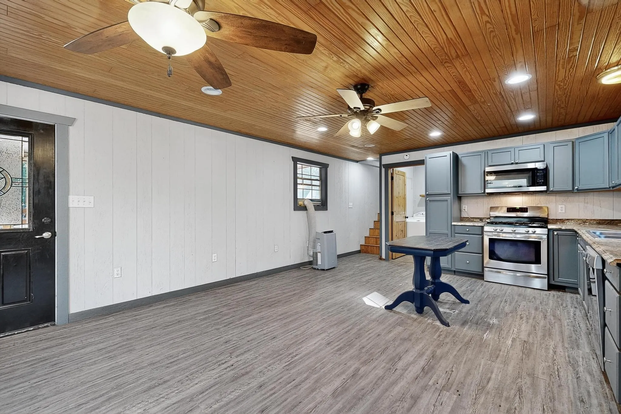 Kitchen with light wood-style flooring, stainless steel appliances, gray cabinets, wood ceiling, and recessed lighting