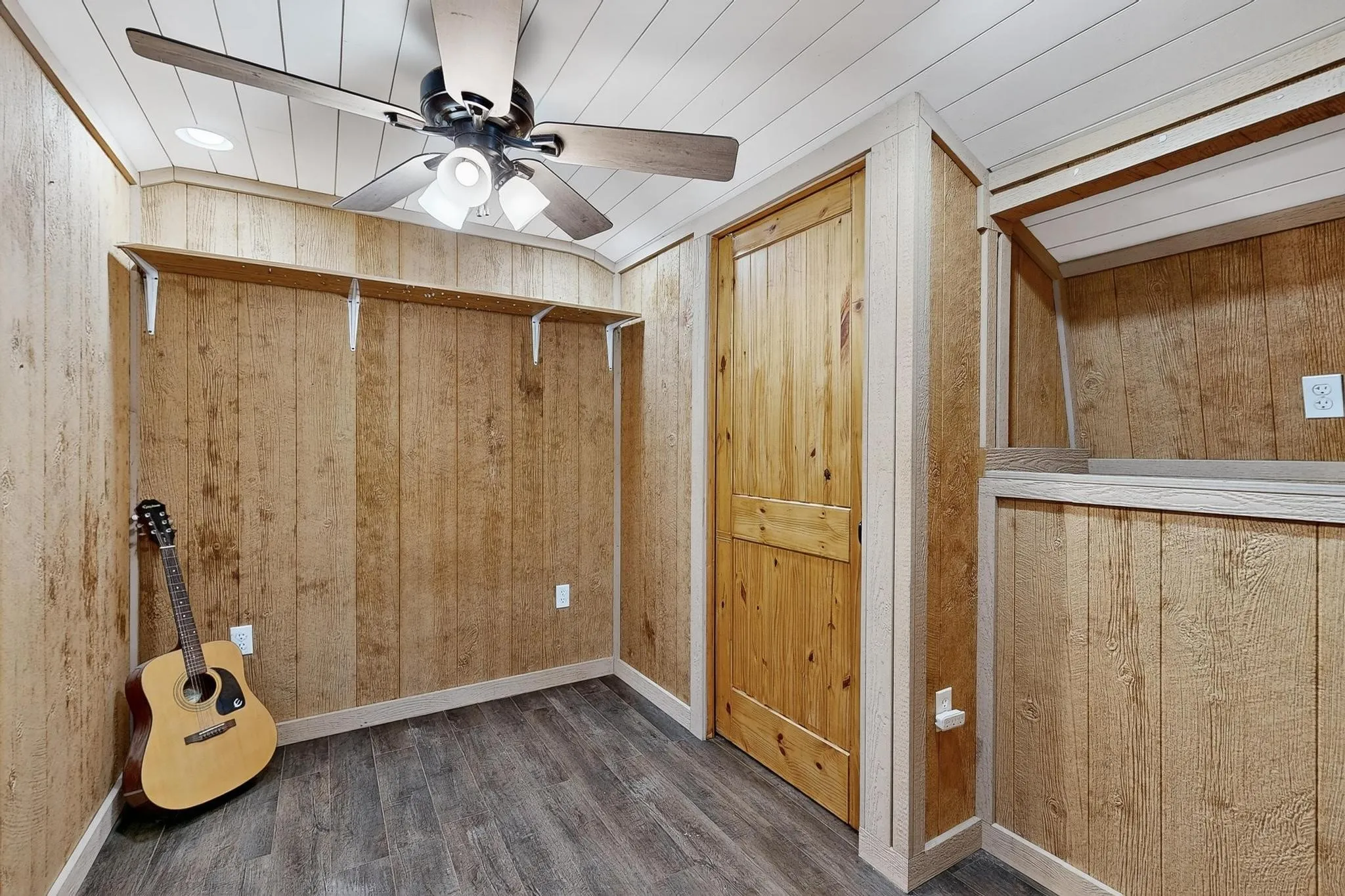 Unfurnished bedroom featuring wooden walls, wood finished floors, and ceiling fan