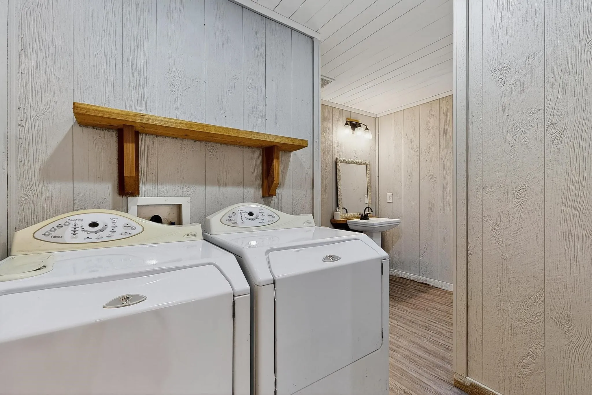 Laundry area featuring wood walls, washing machine and dryer, light wood-type flooring, and wooden ceiling