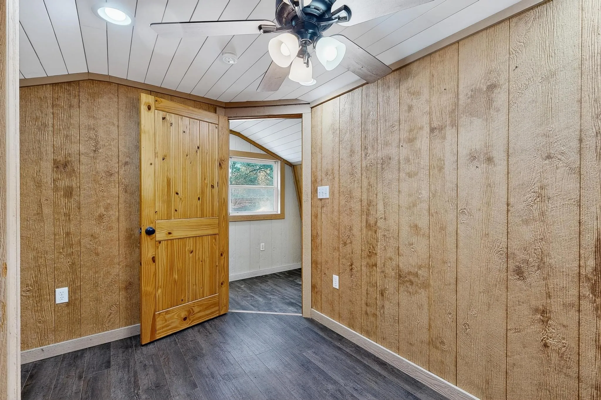 Bedroom with wood walls, dark wood finished floors, ceiling fan, vaulted ceiling, and wooden ceiling