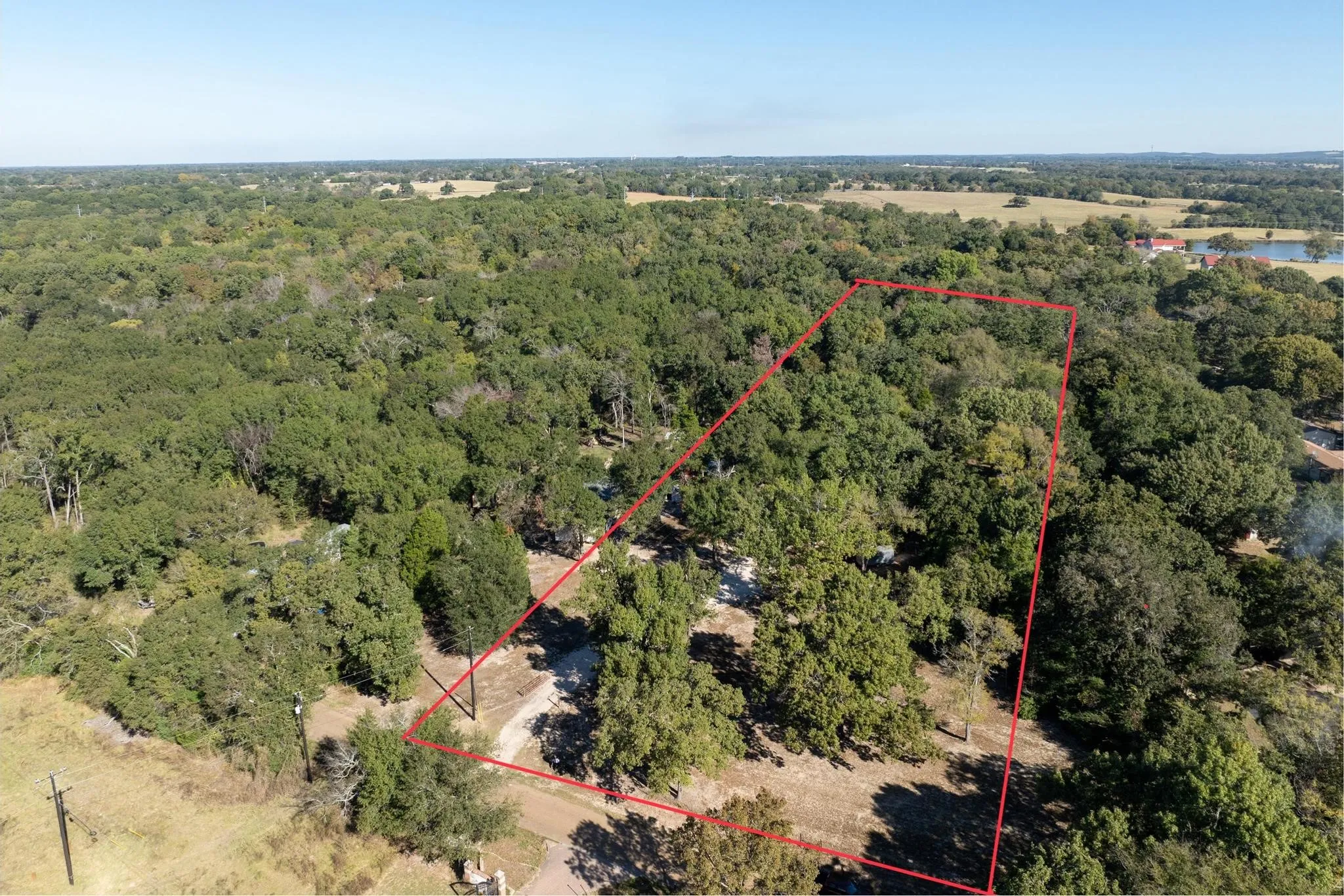 Aerial view of property's location featuring property parcel outlined and a forest