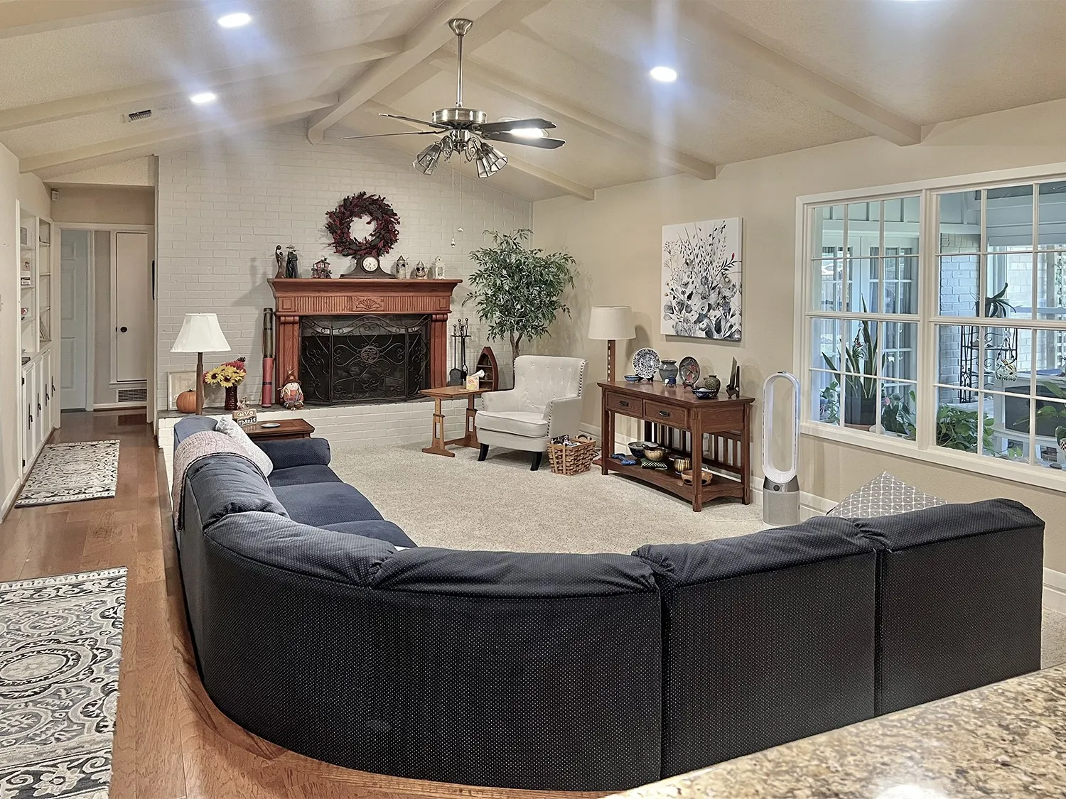 Great room with a fireplace with raised hearth, a ceiling fan, recessed lighting, and wood finished floors