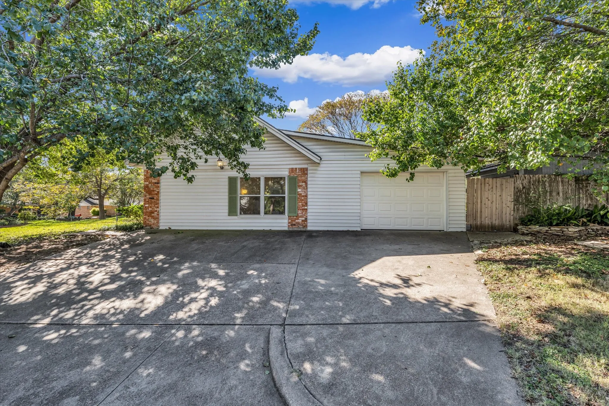 View of front facade with driveway, brick siding, and an attached garage
