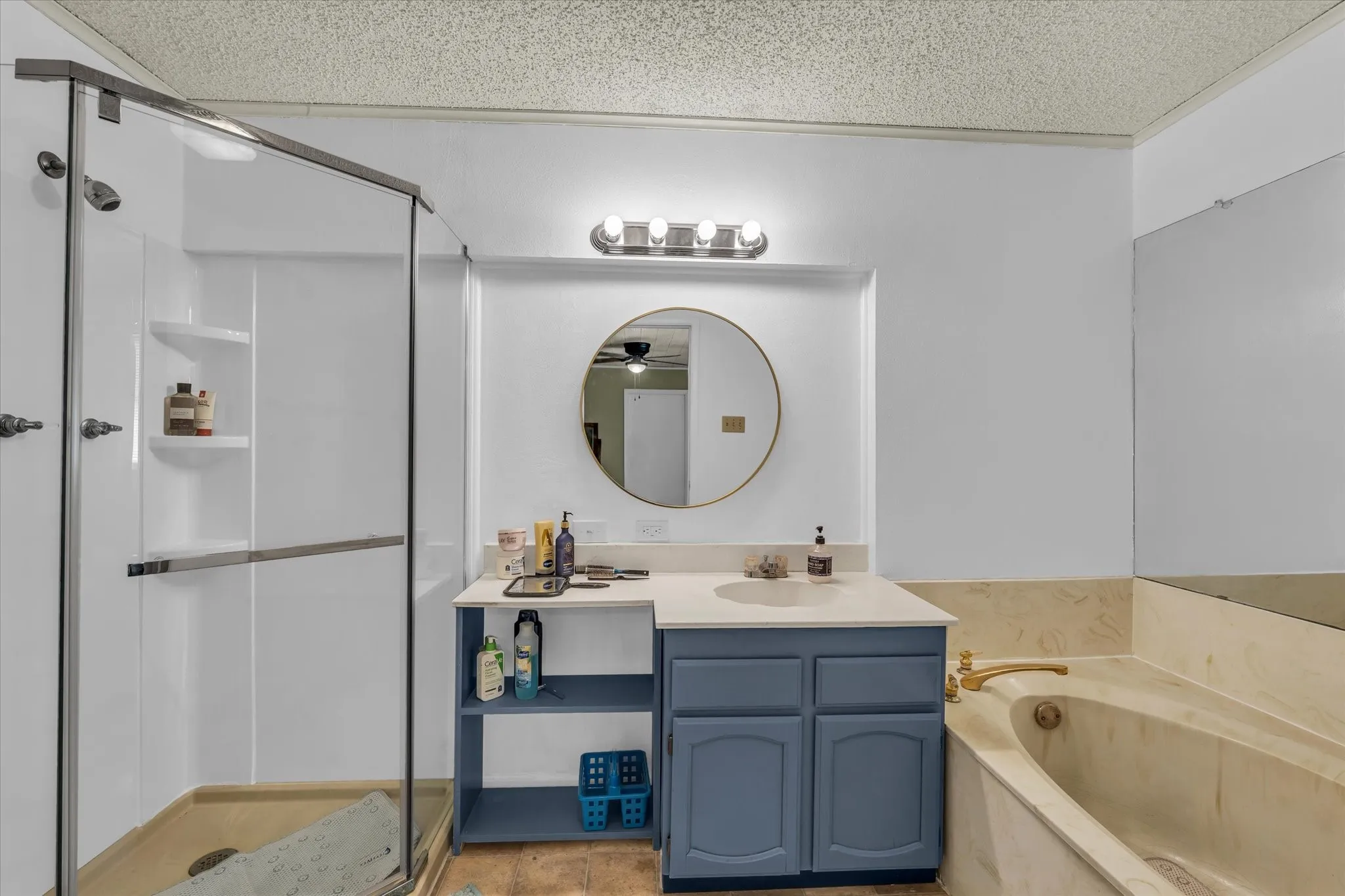 Full bathroom with vanity, a shower stall, a garden tub, a textured ceiling, and light tile patterned flooring