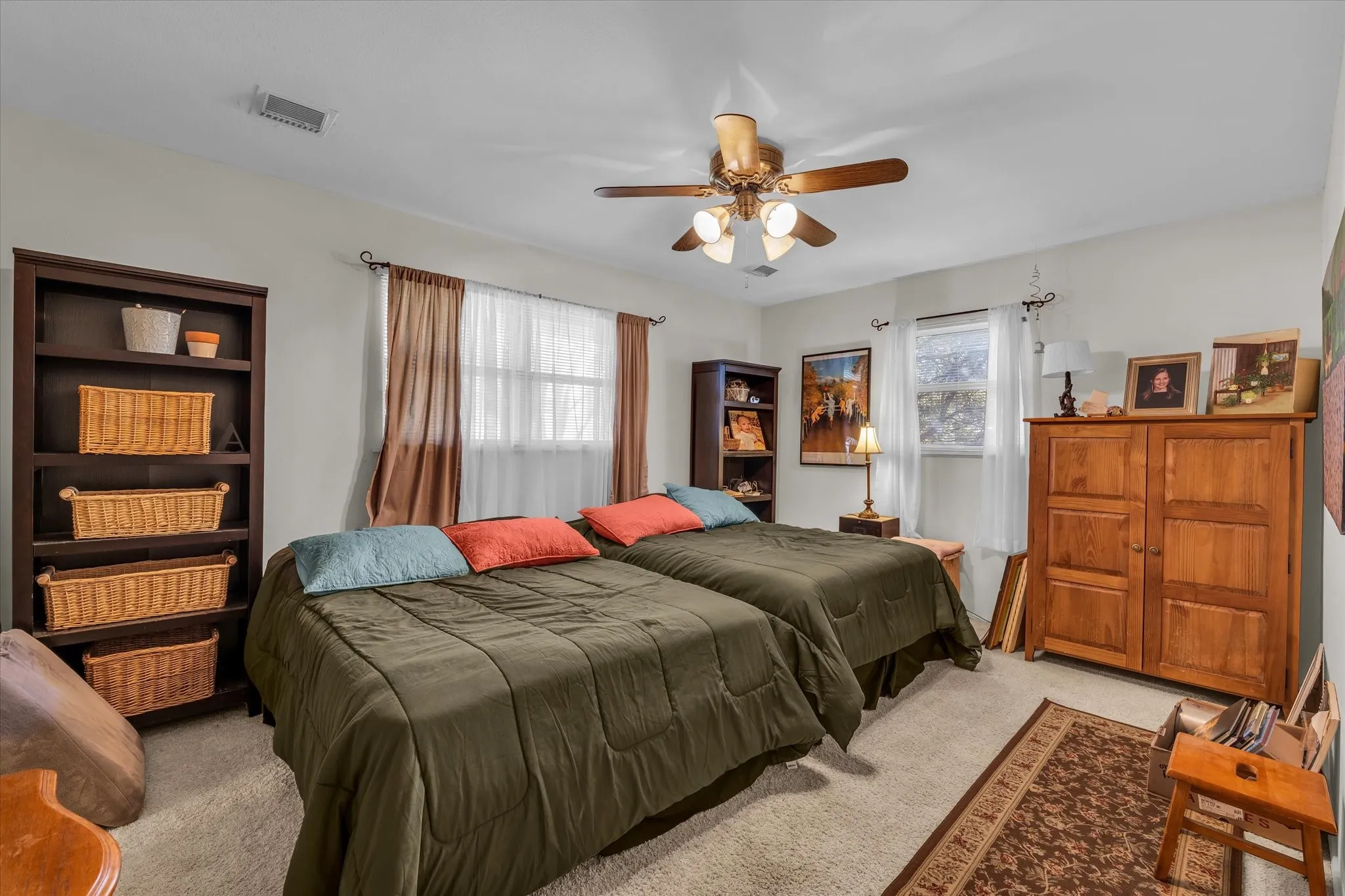 Carpeted bedroom with multiple windows and a ceiling fan