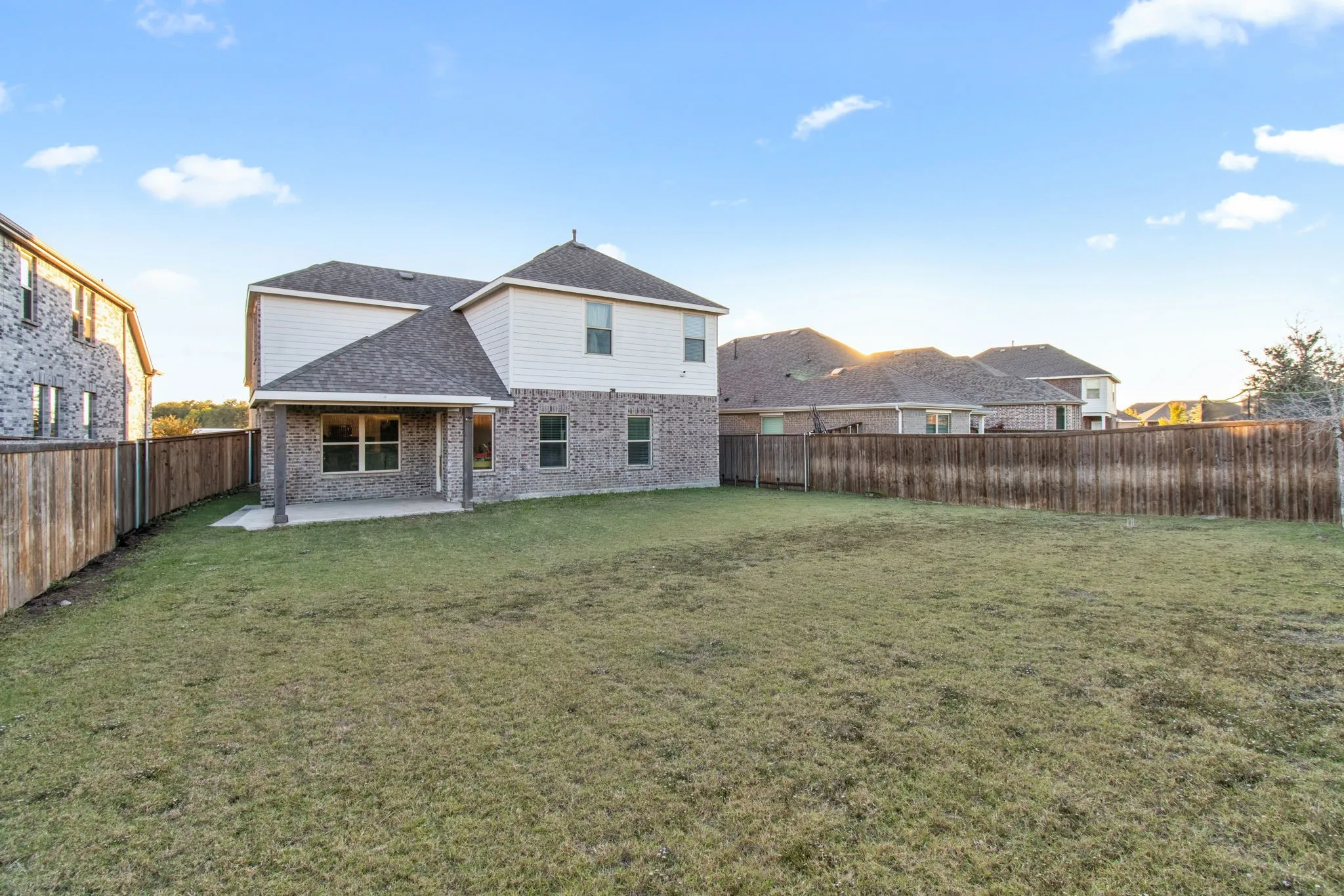 Back of property featuring a patio area, brick siding, a shingled roof, and a fenced backyard