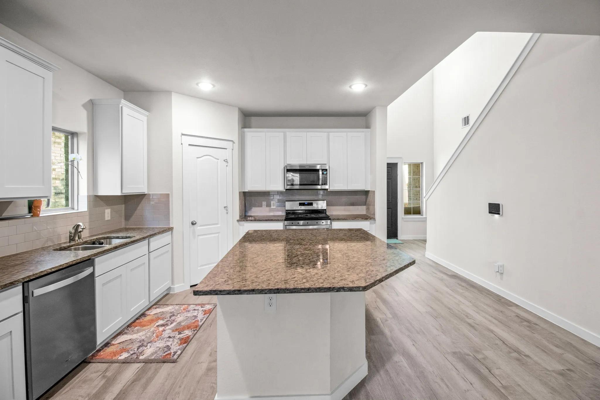 Kitchen with decorative backsplash, dark stone countertops, appliances with stainless steel finishes, light wood-style flooring, and recessed lighting