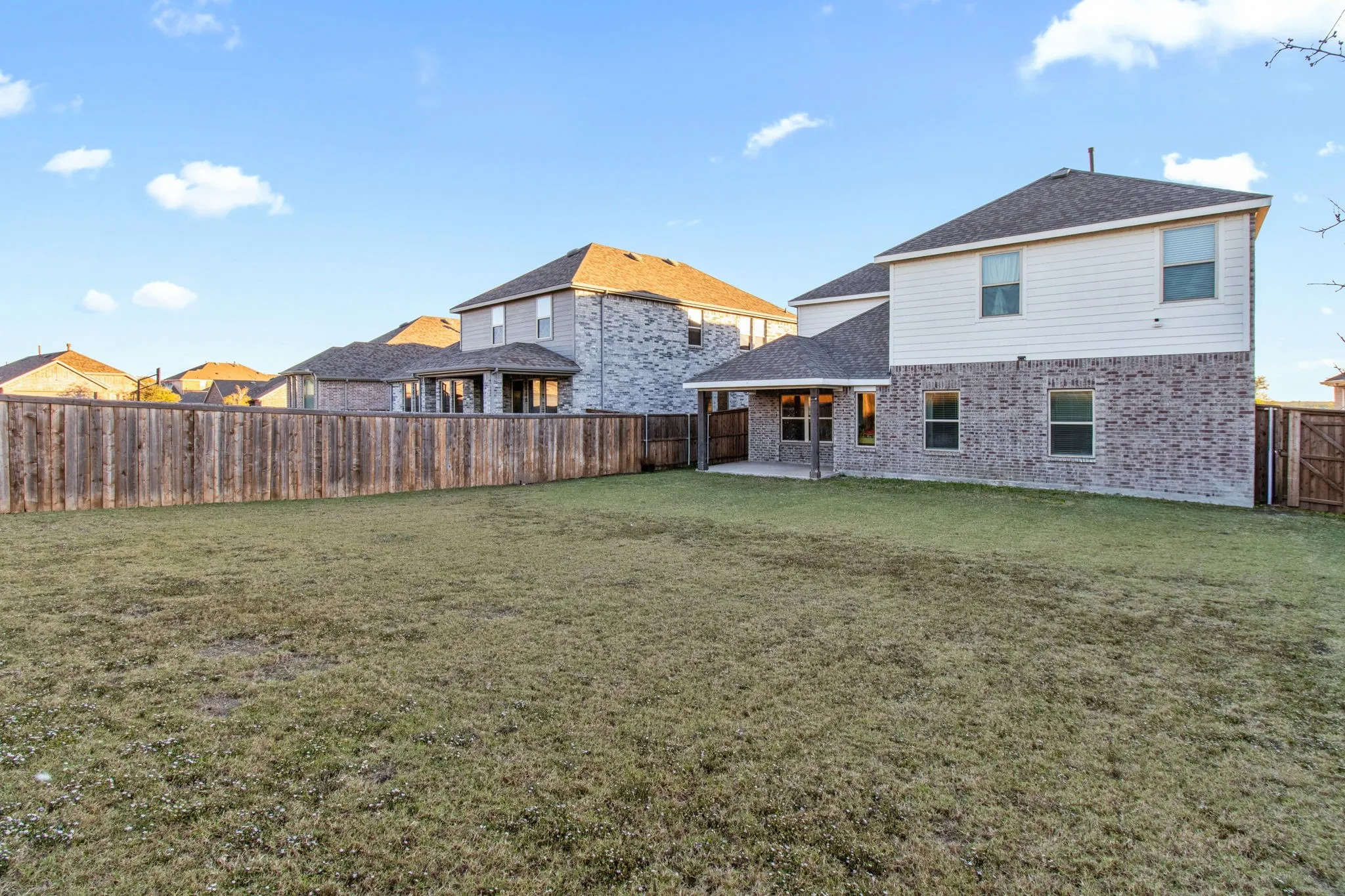 Rear view of house with a patio area, brick siding, a fenced backyard, and a shingled roof