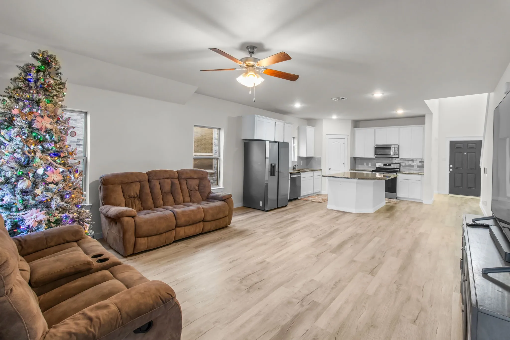 Living room with light wood-style flooring, ceiling fan, and recessed lighting