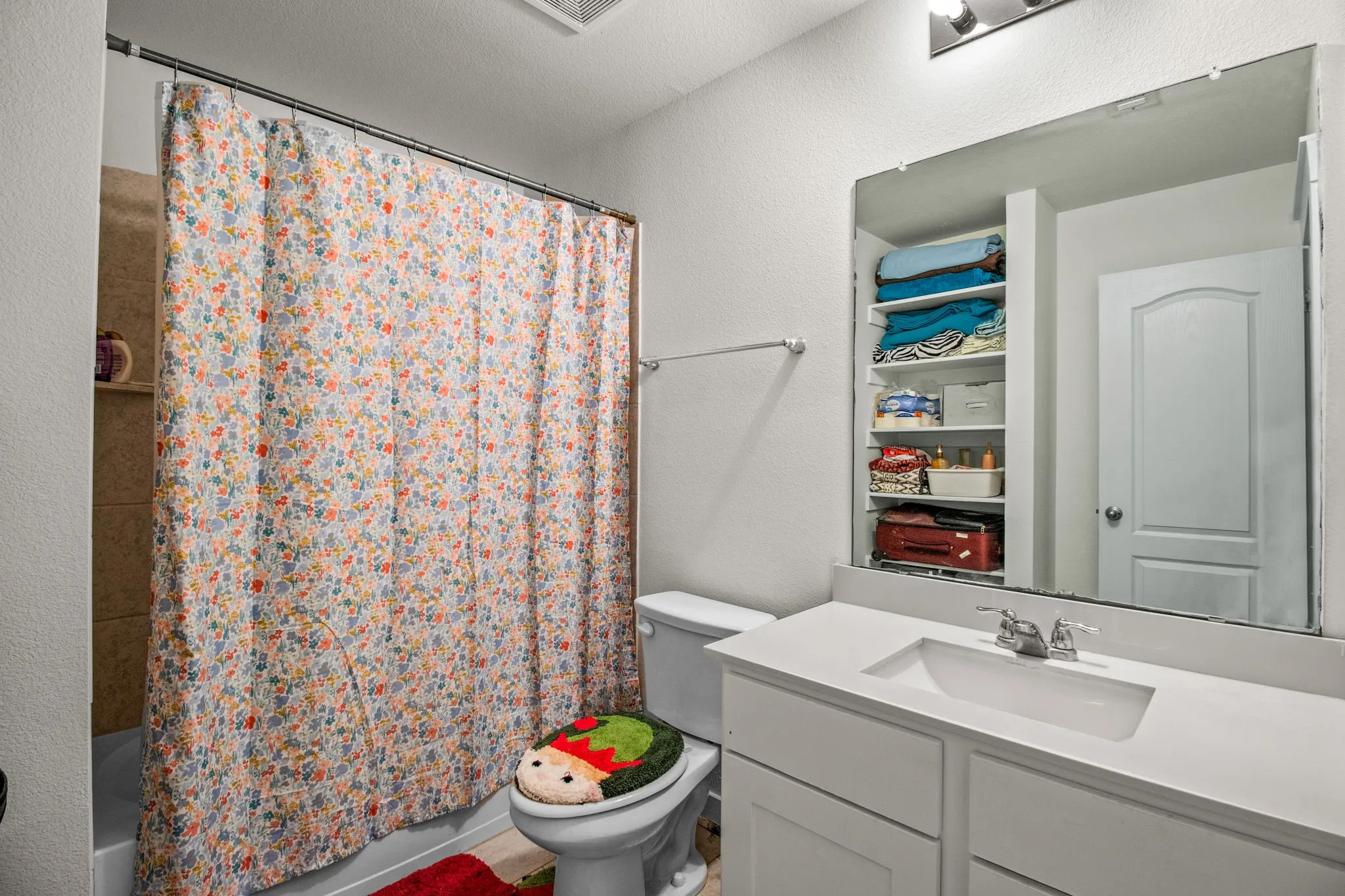 Bathroom featuring vanity, shower / bath combo, and a textured wall