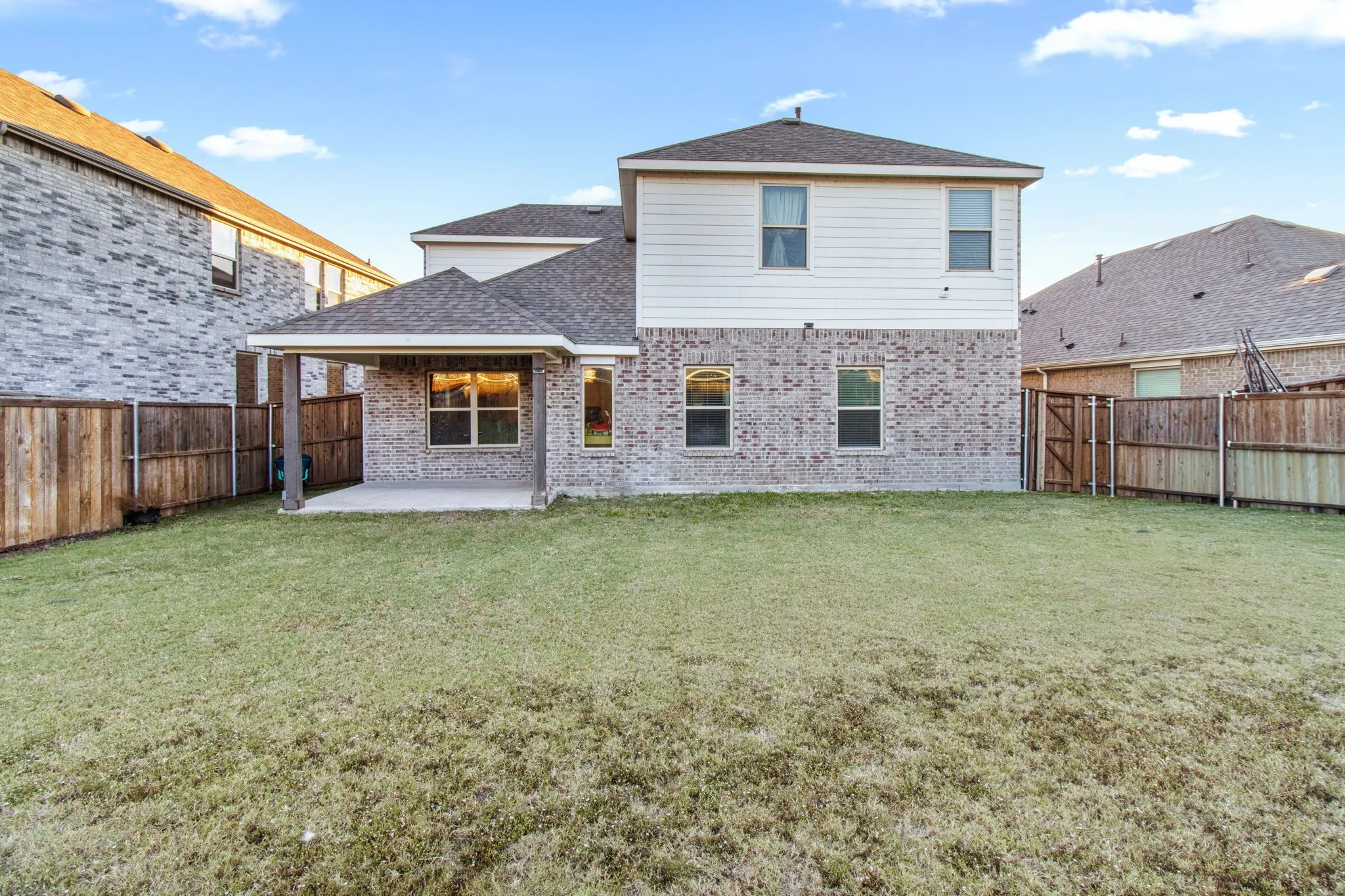 Back of property featuring a patio, brick siding, a fenced backyard, and a shingled roof
