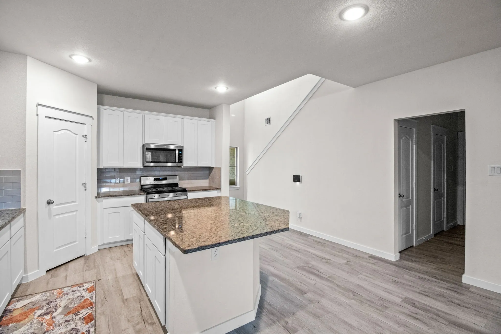 Kitchen featuring decorative backsplash, white cabinetry, appliances with stainless steel finishes, a kitchen island, and recessed lighting