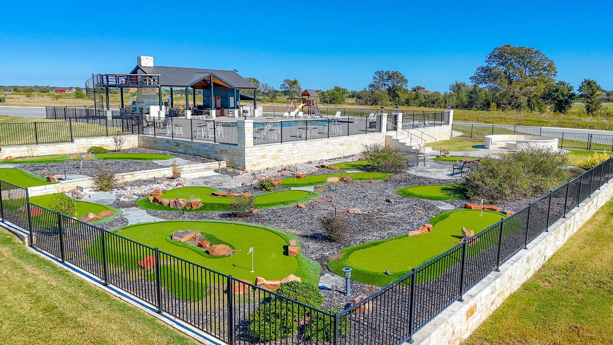 View of property's community featuring a patio, a putting green, a pool, and view of wooded area