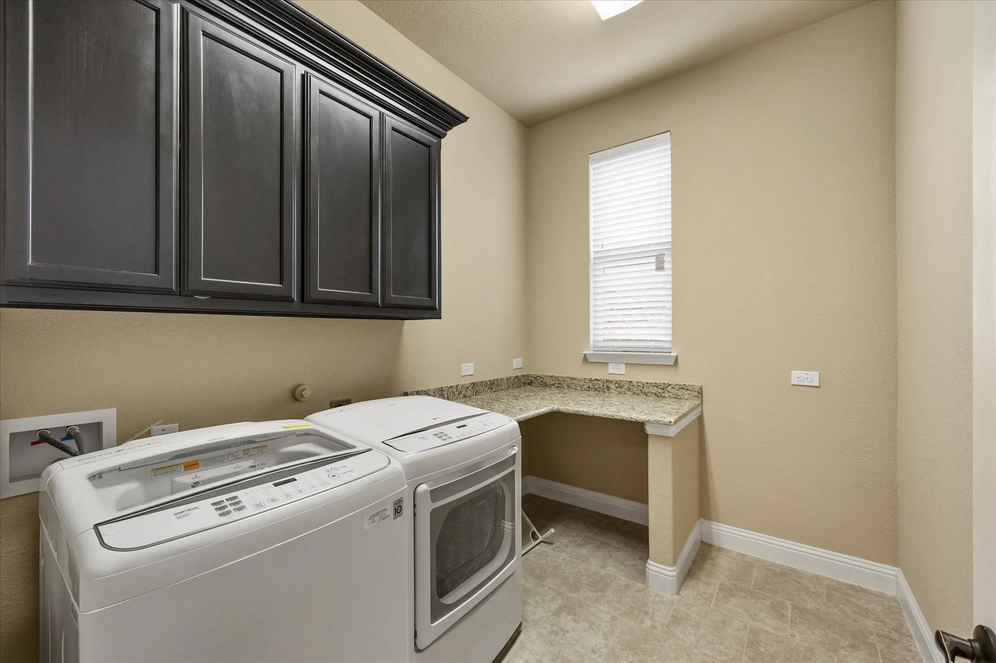 Laundry room includes an abundance of cabinetry, folding area with granite countertops, and space for full size washer and dryer.