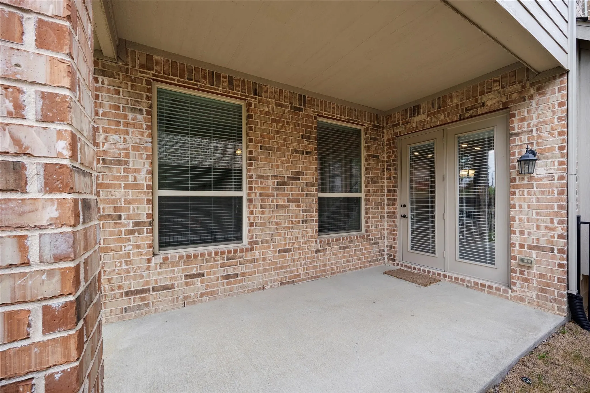 Covered patio overlooks fenced backyard.