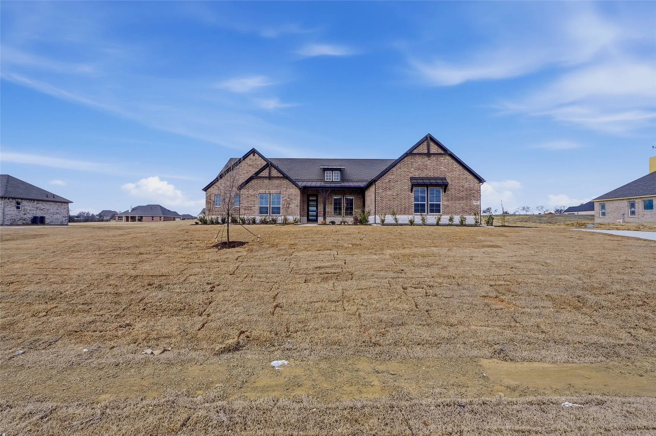 View of front of home with a front lawn, brick siding, and covered porch