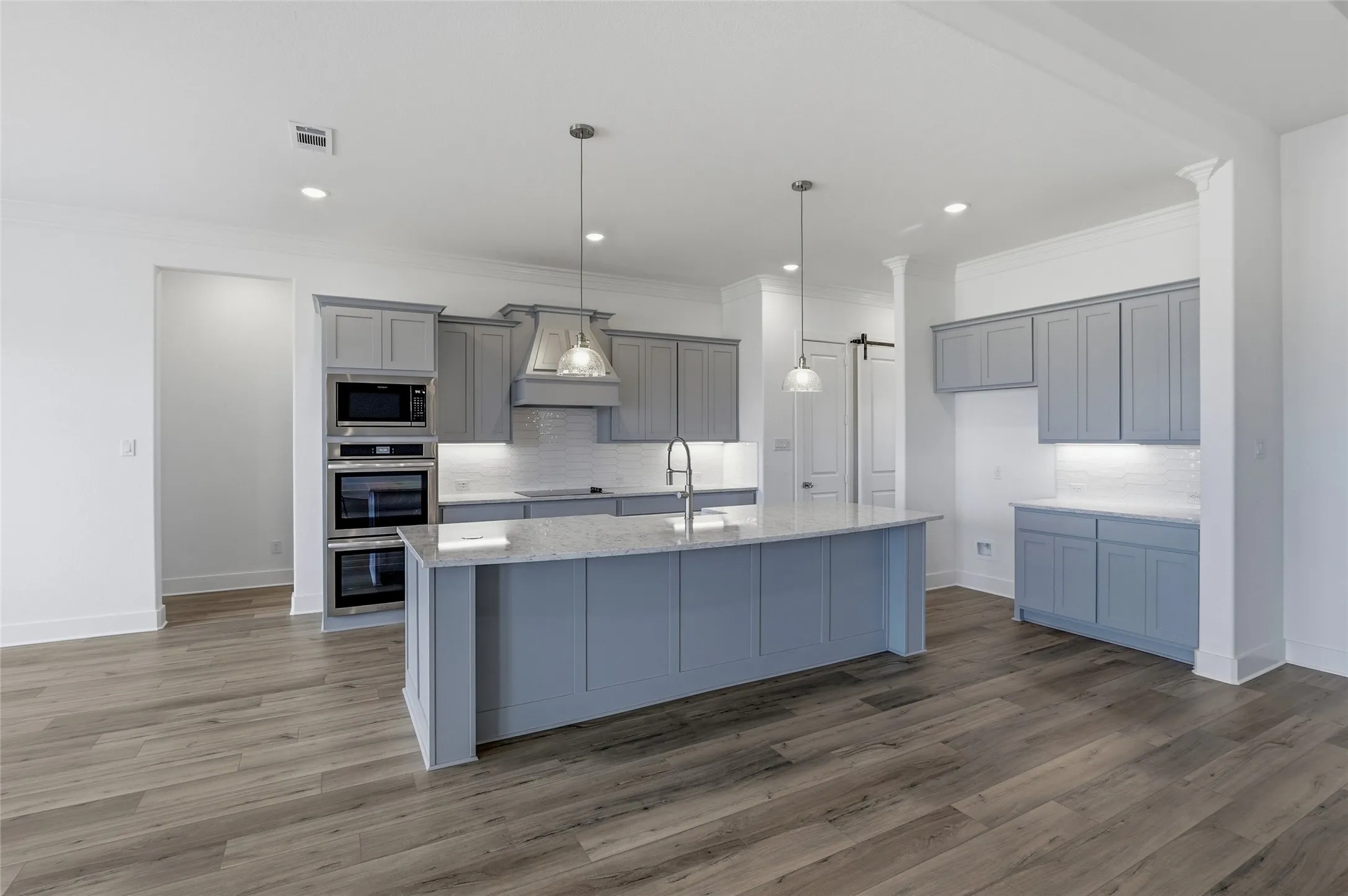 Kitchen with gray cabinets, decorative backsplash, decorative light fixtures, and crown molding