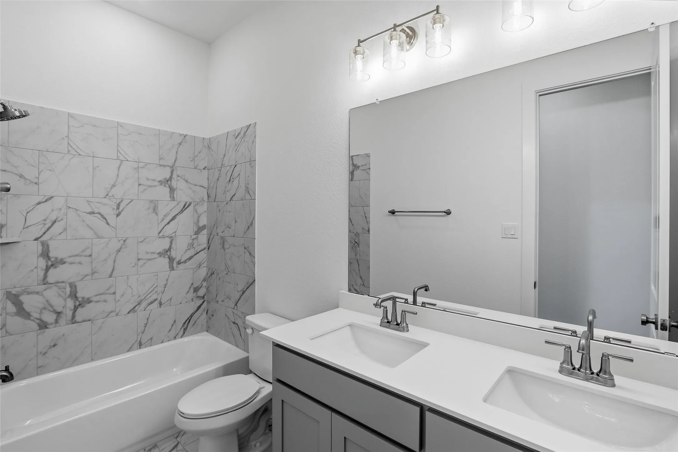 Bathroom featuring double vanity, bathing tub / shower combination, and marble look tiles